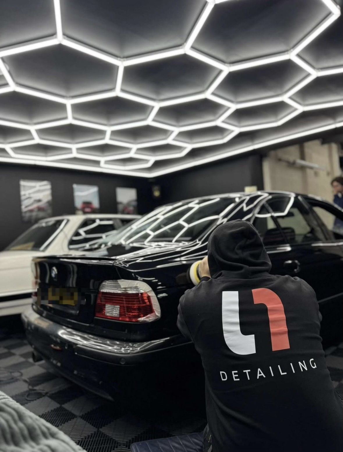 L1 Detailing technician machine polishing a BMW under studio lighting