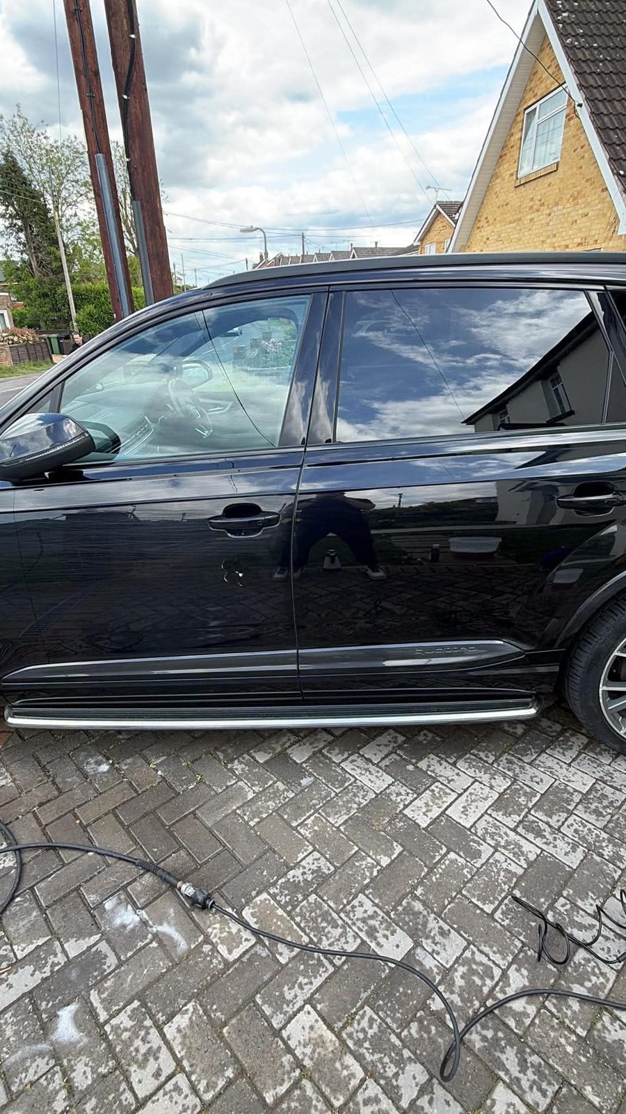 L1 Detailing technician treating a door scratch on a black Audi Q7 in a driveway